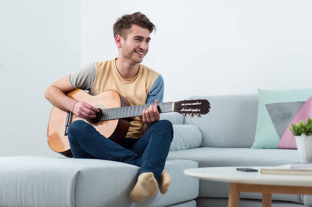Handsome young man playing acoustic guitar - Fotoğraf, Görsel