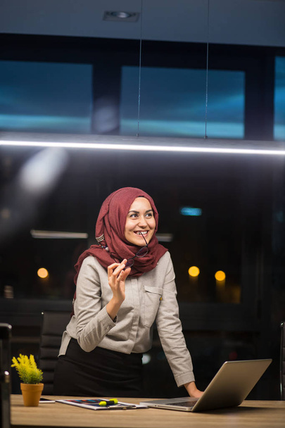 Pretty business hijab woman working alone in dark office - Fotó, kép