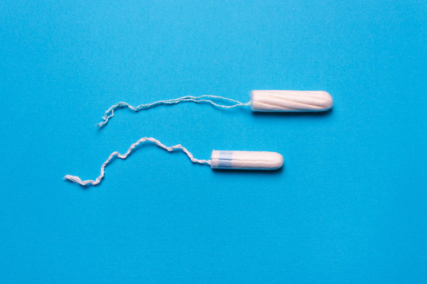 tampon on a blue background. The view is flat. Concept of critical days, menstruation - Photo, Image
