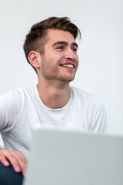 Handsome young smiling businessman working from home with a laptop - Fotografie, Obrázek