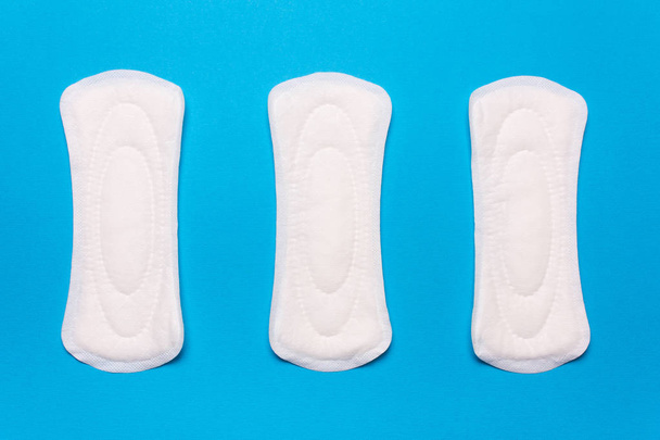 three menstrual pads on a blue background. Concept of critical days, menstrual cycle, menstruation - Photo, Image