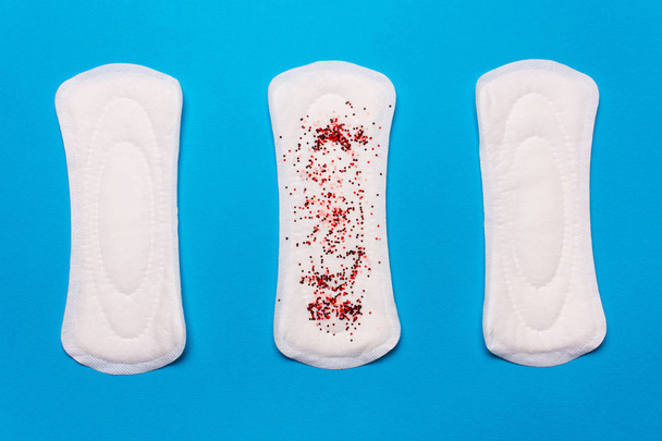 three menstrual pads on a blue background. Concept of critical days, menstrual cycle, menstruation - Photo, Image