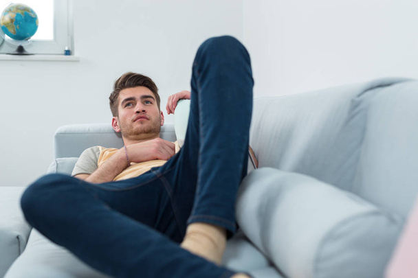 Relaxed man resting lying on a couch in living room - Foto, imagen