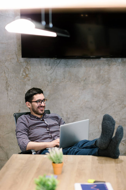 Full length of a relaxed casual young businessman sitting with legs on desk at office - Photo, Image