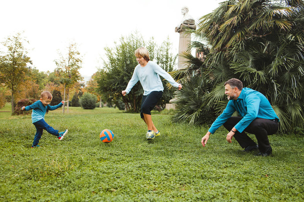 Famille jouant au football dans le parc
 - Photo, image