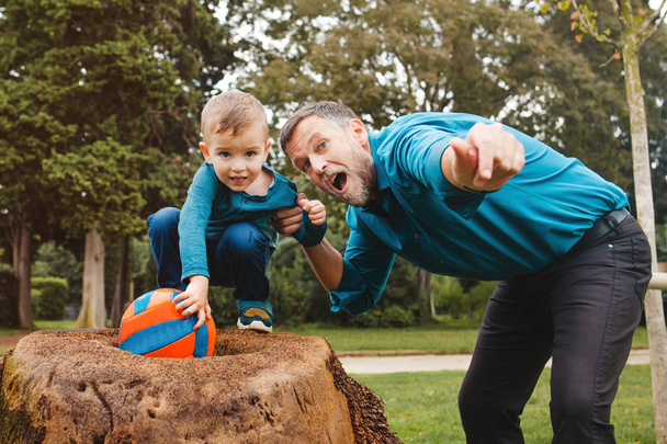 kleiner Junge und sein Vater mit Ball spielen in einem Park - Foto, Bild