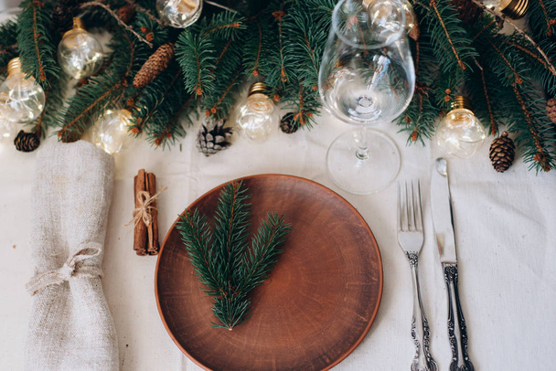 Table with Christmas decorations and garland, ware, green spruce branches - Foto, imagen