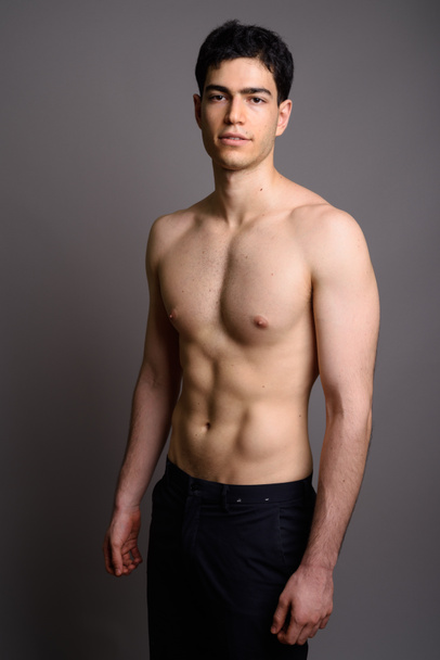 Jonge knappe man shirtloos tegen grijze achtergrond - Foto, afbeelding