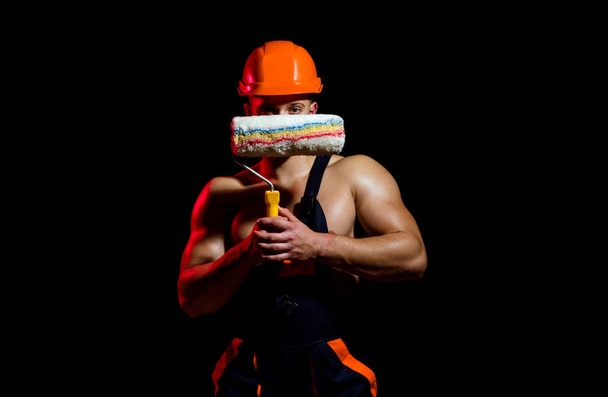 Giving you a professional looking finish. Muscular man at painting work. Skilled painter or decorator man. Construction worker or builder. Worker hold brush roller in muscular hands - 写真・画像