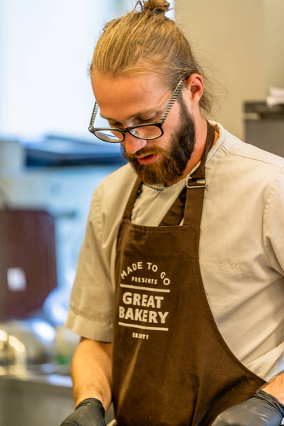 Männlicher Koch schneidet Kürbisse auf gelbem Plastikbrett - Küchensatz - Foto, Bild