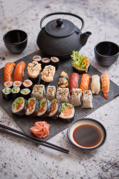 Assortiment van verschillende soorten sushi rolt geplaatst op zwarte stenen bord - Foto, afbeelding