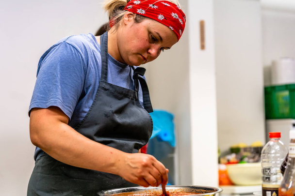 Шеф-кухар жінки рішень томатним соусом з авокадо шматочки в миску з нержавіючої сталі - кухонний гарнітур - Фото, зображення
