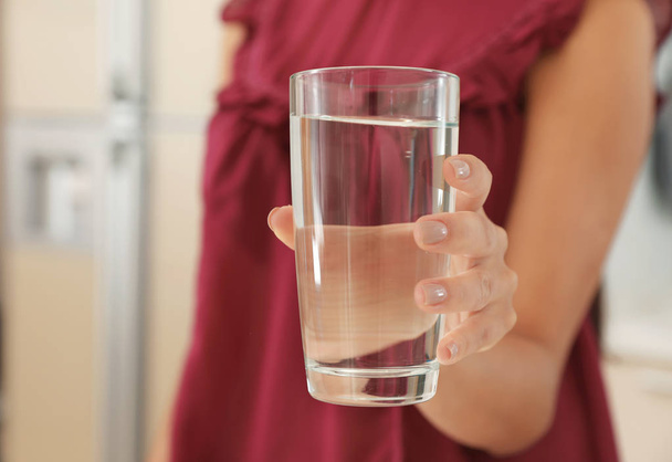 Woman holding glass with pure water in kitchen, closeup - Фото, изображение