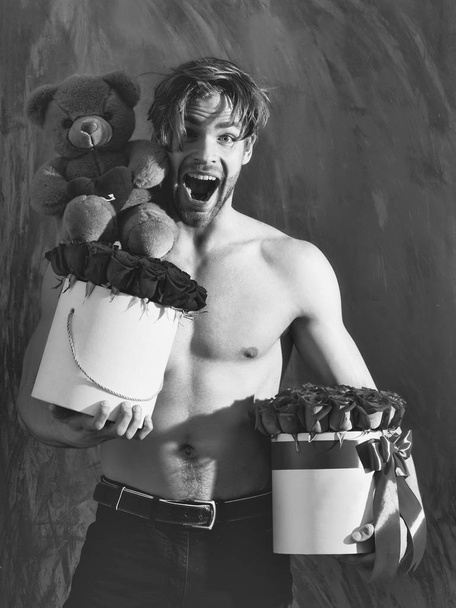 bearded muscular man with sexy body holds red rose box - Foto, Imagen