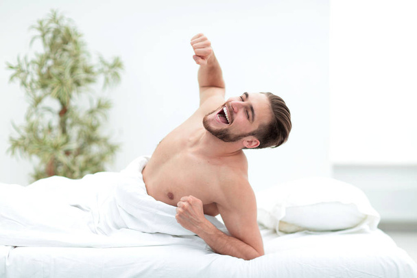 successful man yawns, lying in the bedroom - Zdjęcie, obraz