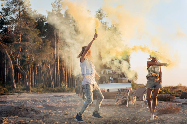 Couple of travelers living in mobile home holding colorful fire bombs - Фото, изображение