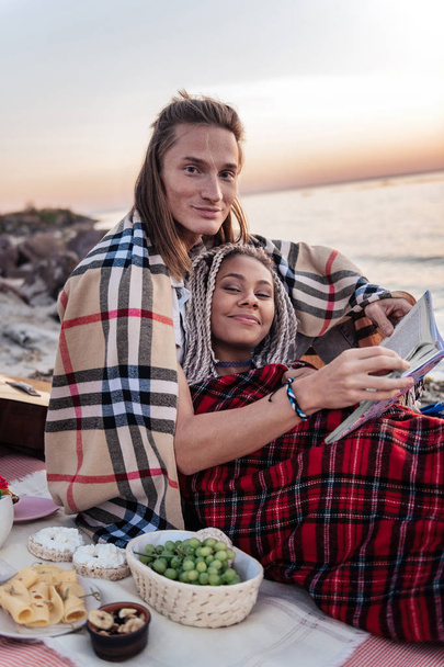 Cute happy couple having romantic dinner with grapes and cheese on beach - Photo, Image