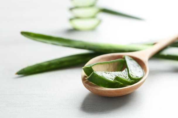Wooden spoon with slices of aloe vera on light table. Space for text - Foto, Imagem