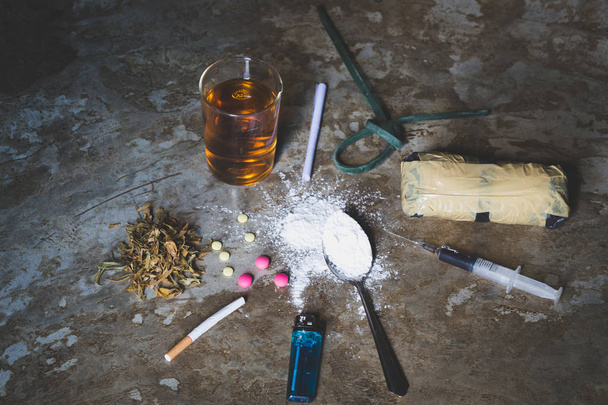 様々 な種類の床の上の人間の頭蓋骨の薬、ハード別のコレクション薬ヘロイン、丸薬、マリファナ、タバコとアルコールの依存症の概念 - 写真・画像