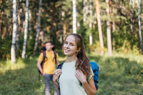 couple of tourists with backpacks hiking in a forest - Photo, image