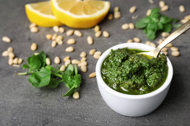 Homemade basil pesto sauce in bowl and ingredients on table - Foto, Imagem