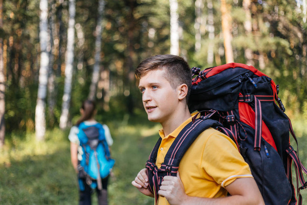 couple of tourists with backpacks hiking in a forest - Фото, зображення