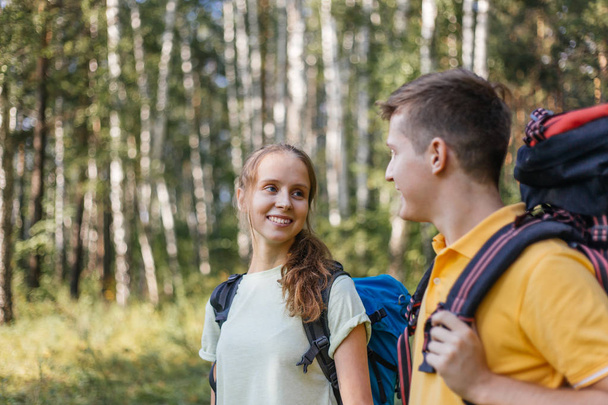 couple of tourists with backpacks hiking in a forest - Foto, imagen