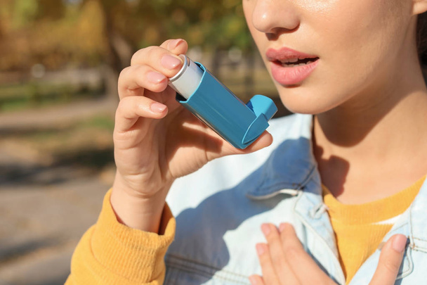 Woman using asthma inhaler outdoors. Health care - Photo, image