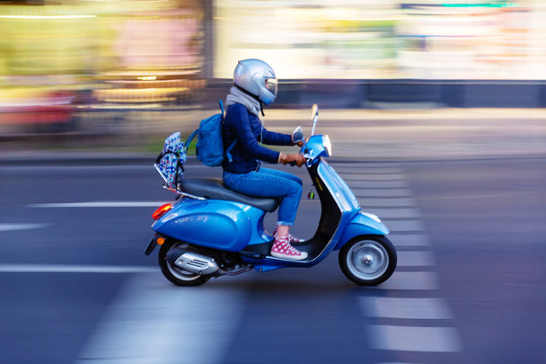 young woman with a scooter on the move in the city with motion blur effect - Fotó, kép