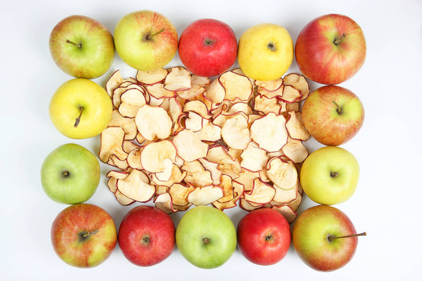 Gedroogde appel segmenten omringd door verse appels op witte achtergrond - Foto, afbeelding