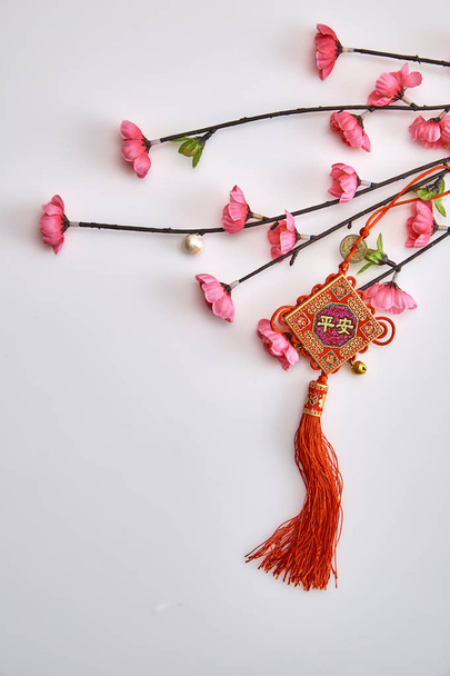 Plum Pink Cherry Branch with Chinese Lucky Knot on white background Chinese New Year decorations (English translation for foreign text means blessing) - Photo, Image