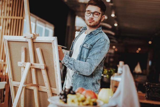 Portrait of Guy Painting on Easel Still Life. Handsome Professional Caucasian Talanted Painter Artist in Casual Clothes Looking at Fuits Standing in Bright Room. Art Education - Fotografie, Obrázek