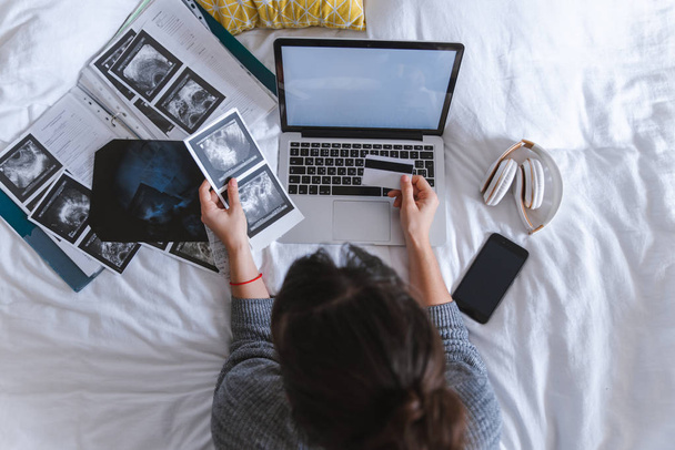 american young adult woman check medical results holding card in hand. laptop with white screen on the bed. copy space. healthcare concept.. health insurance - Foto, imagen