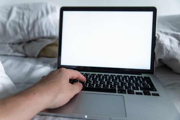 man working in bed on laptop. white screen. copy space - Photo, image