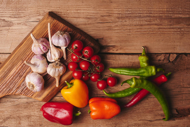 Fresh organic vegetables on wooden board close up. Cherry tomatoes, garlic, peppers and dill on a wooden table - Foto, imagen