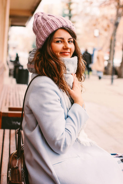 Young beautiful woman in coat and hat in late autumn or winter on city street enjoying life - Zdjęcie, obraz