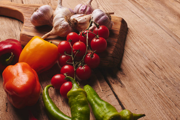Свежие органические овощи на деревянной доске закрываются. помидоры черри, чеснок, перец и укроп на деревянном столе
 - Фото, изображение