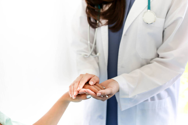 Beautiful Doctor consulting and holding hand patient reassuring with care. - Photo, image
