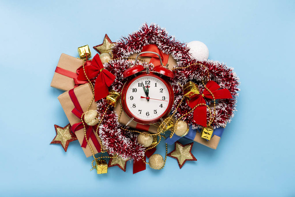 Red alarm clock, Christmas decorations, gifts on a blue background. Merry Christmas and happy new year concept. Flat lay, top view. - Photo, Image