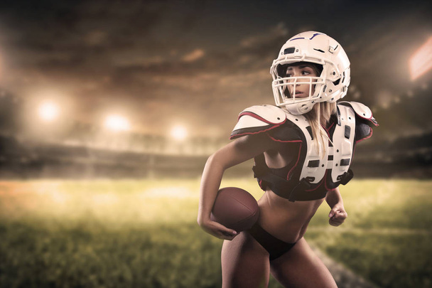 Amerikai futball nő játékos tartja a labdát a panoráma stadion sisakot viselő - Fotó, kép