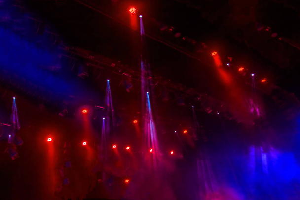 Luzes de palco. Vários projetores no escuro. Feixes de luz multicoloridos dos holofotes do palco no palco na fumaça no momento do show de entretenimento. Clube nocturno. As luzes mostram-se. Espectáculo Lazer
 - Foto, Imagem