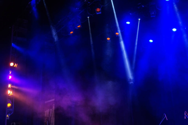 Luces de escenario. Varios proyectores en la oscuridad. Rayos de luz multicolores de los proyectores del escenario en el escenario en el humo en el momento del espectáculo de entretenimiento. Un club nocturno. Espectáculo de luces. Lazer show
 - Foto, Imagen