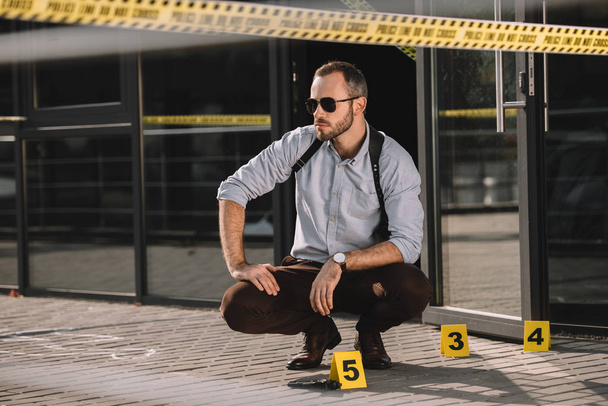 thoughtful male detective sitting at crime scene - 写真・画像