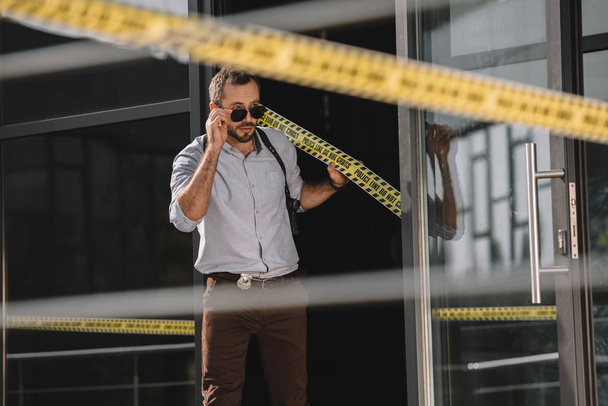  male detective straightening sunglasses holding on the cross line - Photo, Image