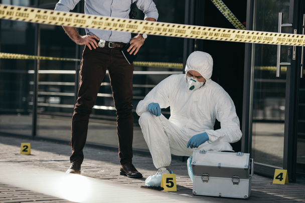 cropped view of male detective looking at work of criminilogist - 写真・画像