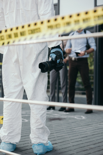 visão recortada do criminologista em terno protetor e luvas de látex com câmera na cena do crime
 - Foto, Imagem