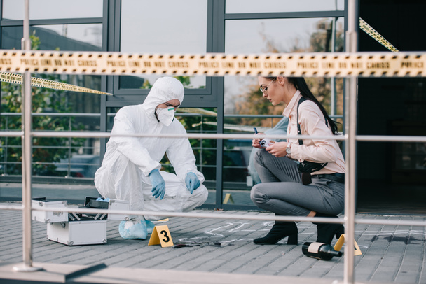 feamale detective and male criminologist inspecting the crime scene - 写真・画像