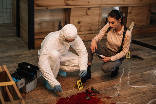 forensic investigator and female detective taking notes and examining crime scene together - Photo, Image
