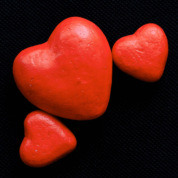 Drie rood hart van verschillende grootte op donkere achtergrond. - Foto, afbeelding