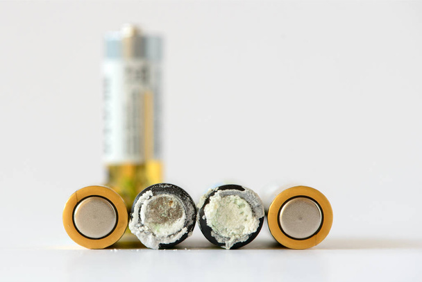 The old battery was leaking hazardous waste. Isolated background. Alkaline batteries. The group used a new disposable batteries - Photo, Image